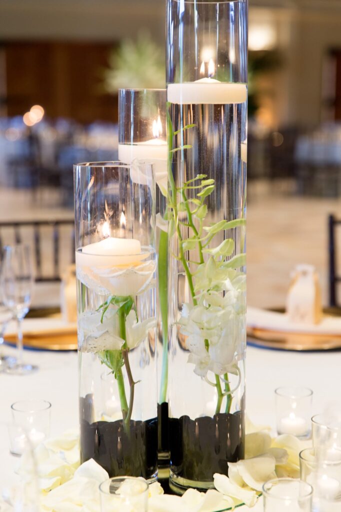 Plants and candles placed inside tall glass jars filled with water.