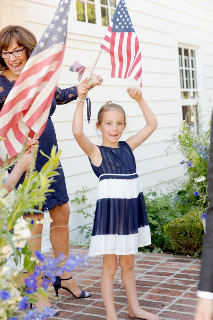 Cute little girl raises the American flag in her arm.