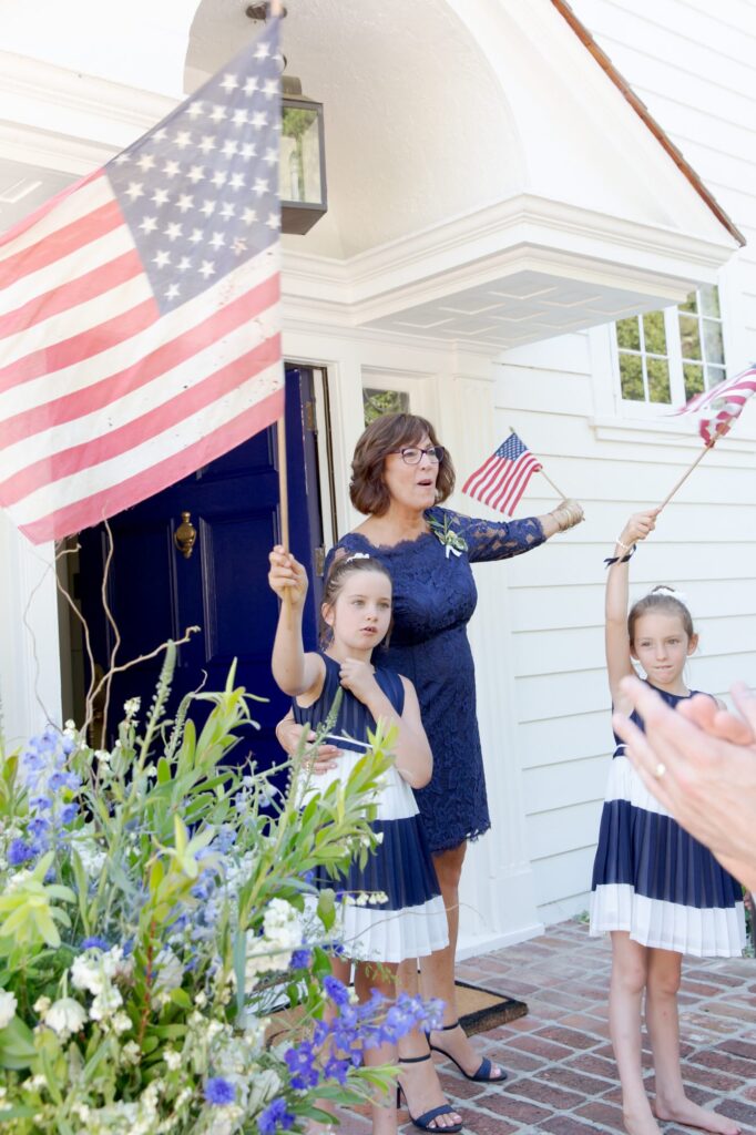 Proud lady teaches patriotic little girls to wave their American flags.