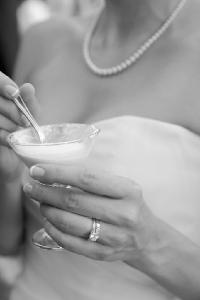 Bride in her wedding gown holds a cup of desserts.