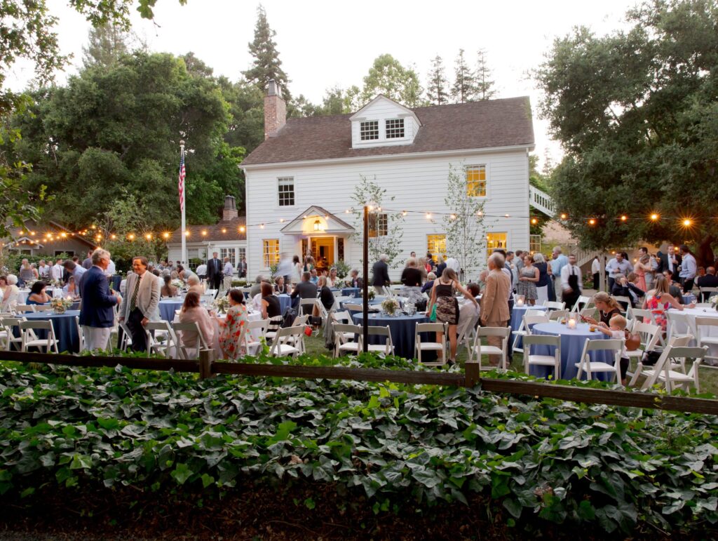 Wedding reception party bustling with guests, all elegantly dressed, mingling and enjoying the evening. 