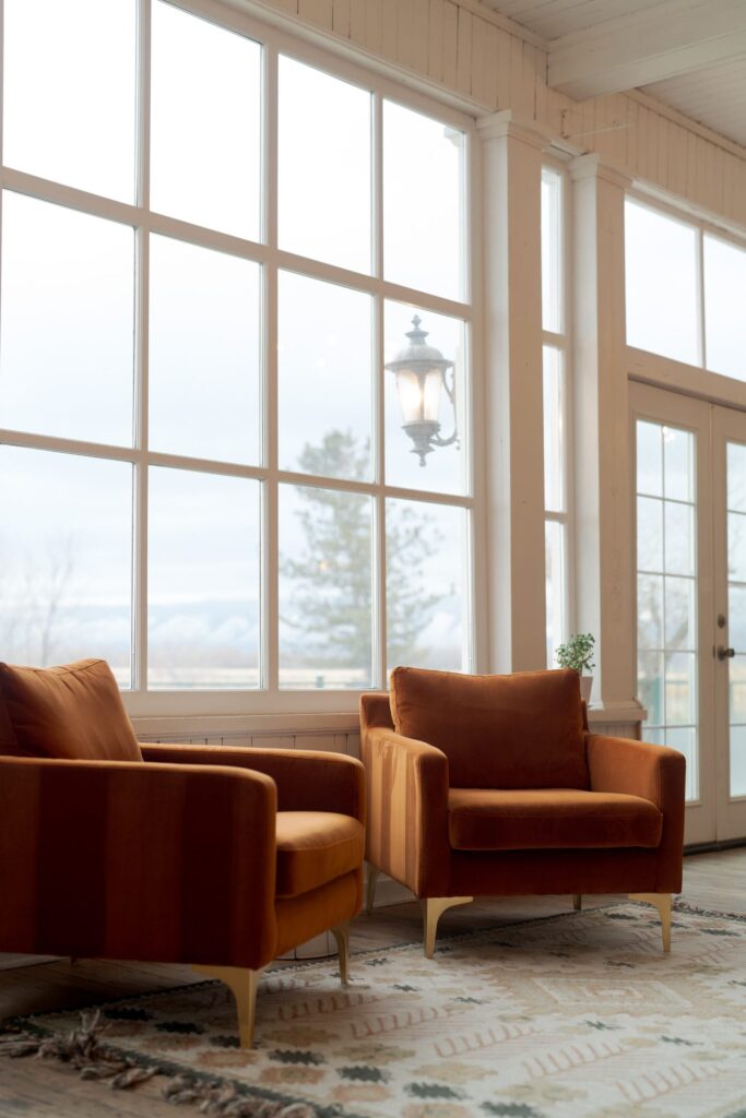 A cozy seating area featuring two orange armchairs with gold legs placed on a patterned rug. 