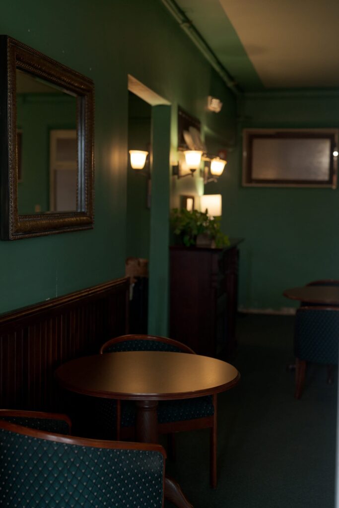 Dimly lit room with green walls and a round wooden tabletop.