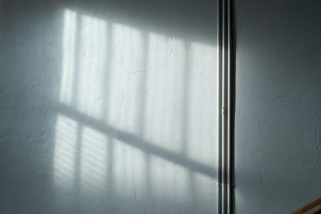 A minimalist image showing the play of light and shadow on a textured white wall.