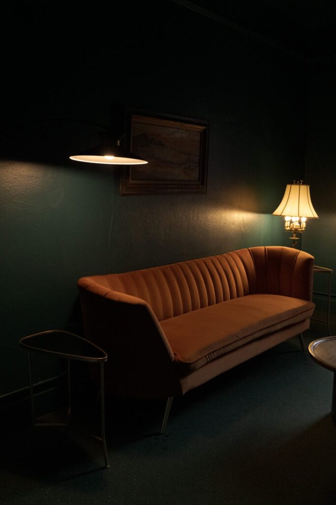 A dark living room with a retro-style orange sofa against a dark green wall