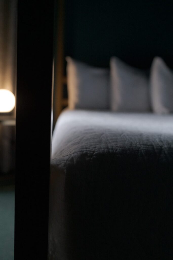 Bedside with round lamp emitting soft lighting.