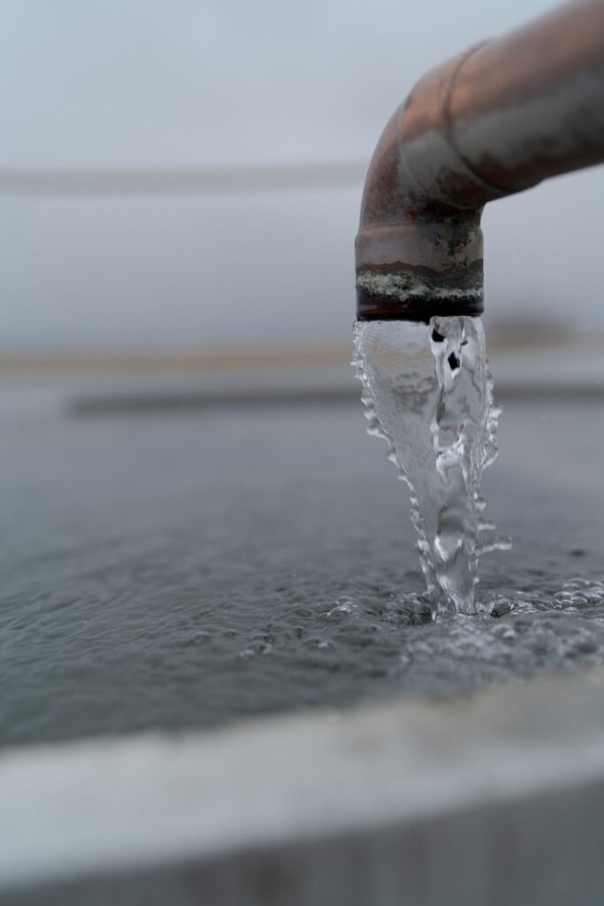 Water flows from a pipe into the concrete tank.