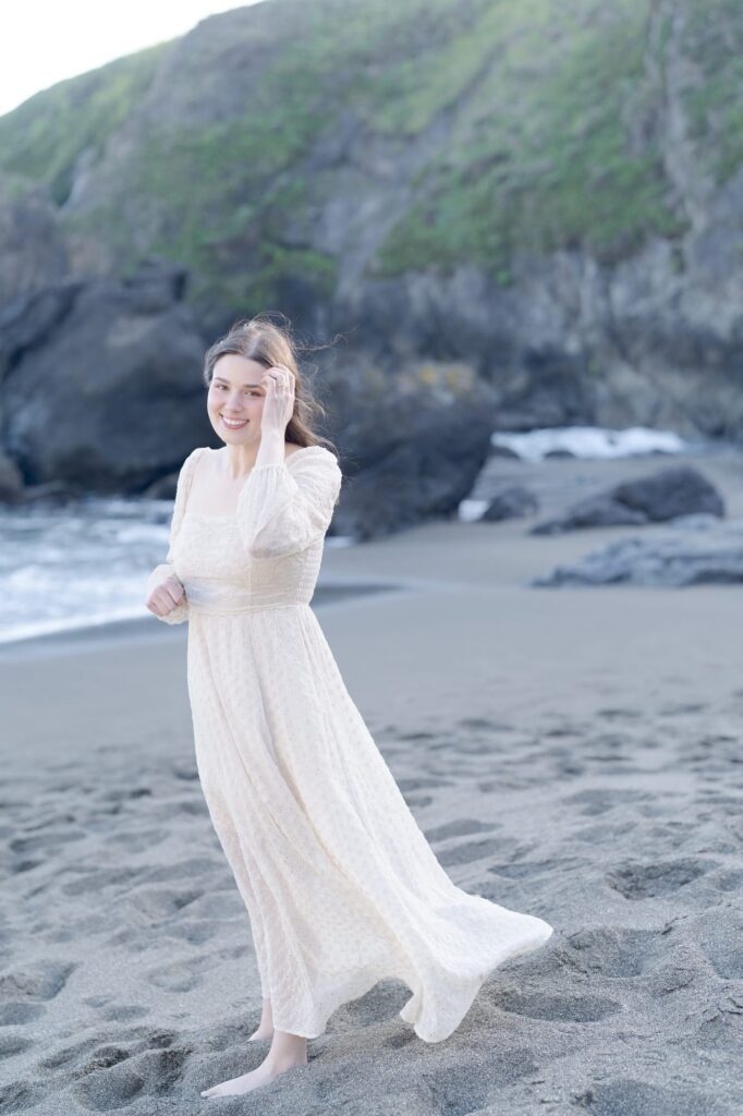 Girl in plain white gown smiles at the beach