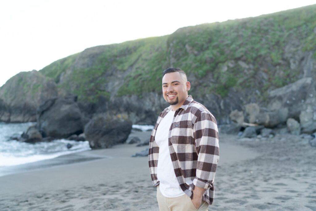 Middle-aged man with black hair and goatie at the beach.