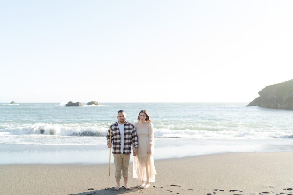 Man with a stick poses at Bodega Bay with his fiancee.