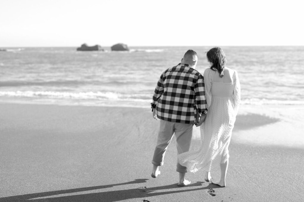 Newly engagement couple hold hands and turn to Bodega Bay