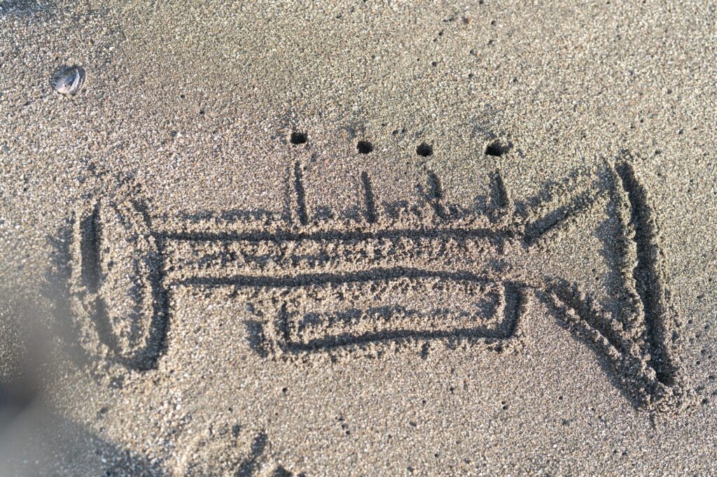 Trumpet figure drawn on beach sand.