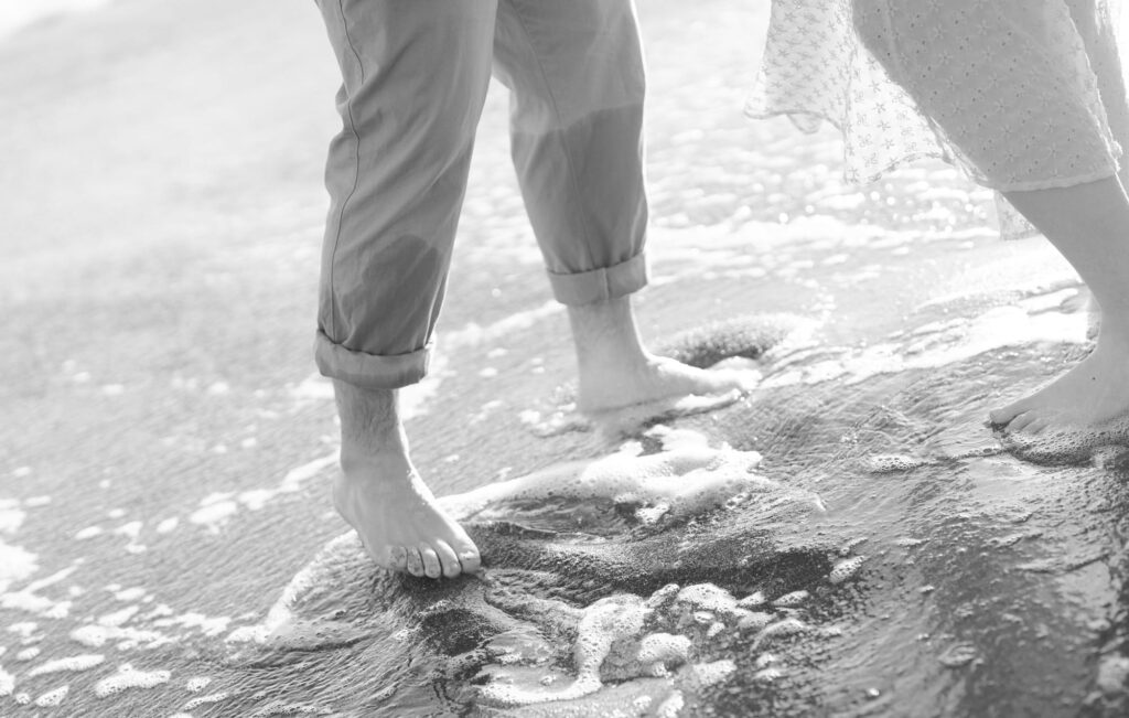 Newly engaged couple move their feet in fizzy waters of Bodega Bay.