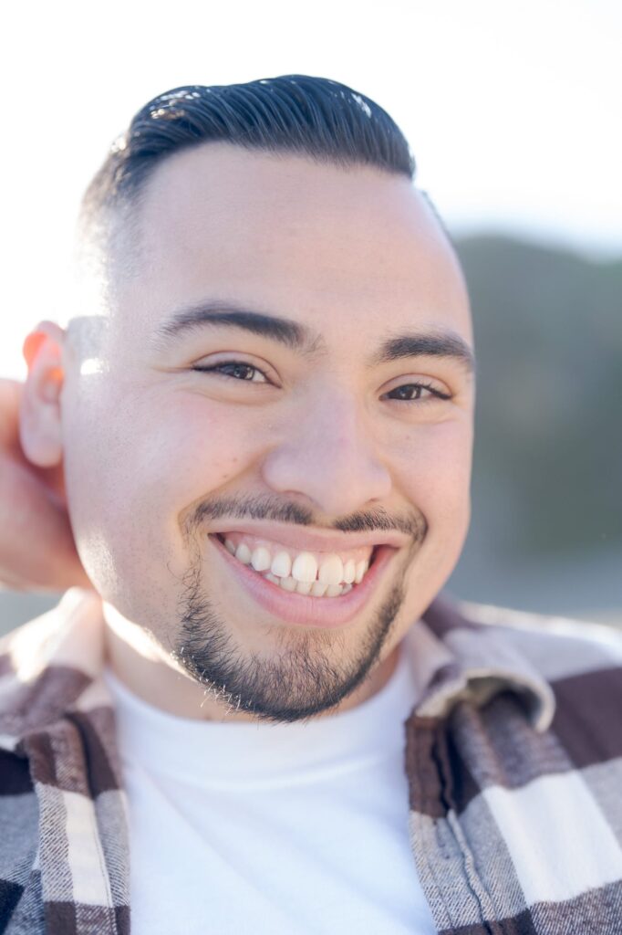 Man with pretty eyes and eyebrows smiles at the camera.