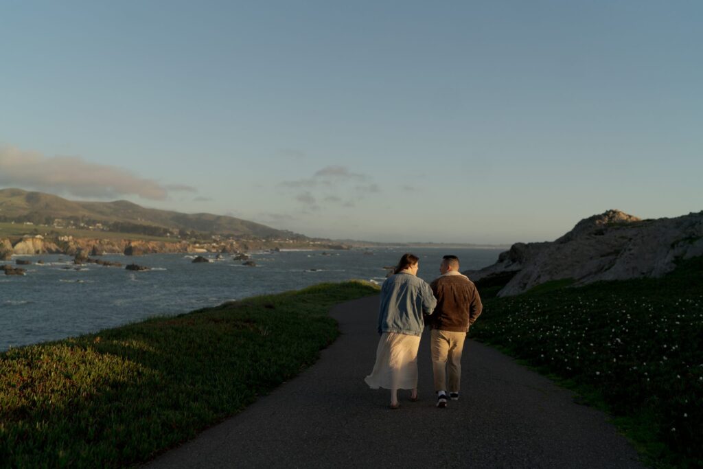 Warm, soft sunlight falls on a newly engaged couple as they walk through Bodega Bay.