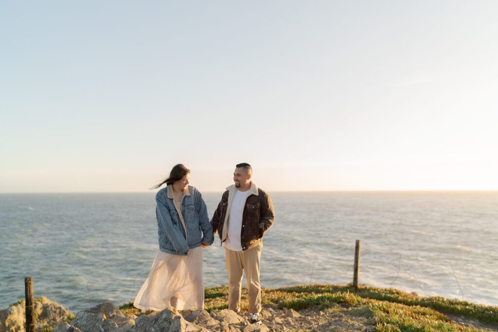 Newly engaged couple hold hands and look into each others' eyes at Bodega Bay.