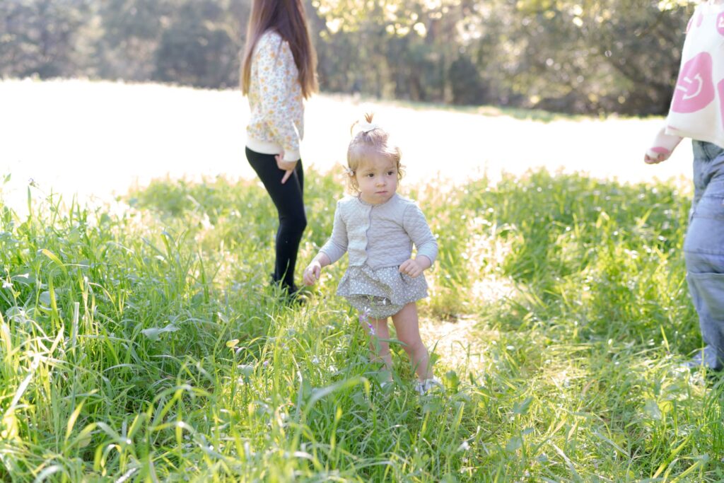 Little baby girl walks amidst tall grasses of California.