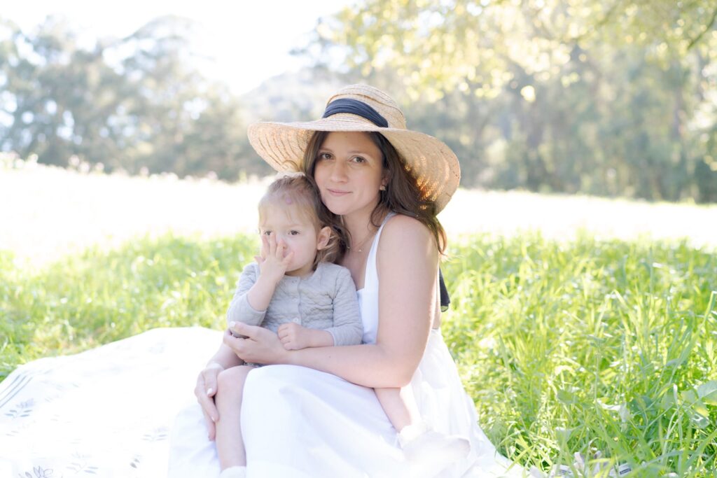 Jilian wears a hat and holds her baby daughter.