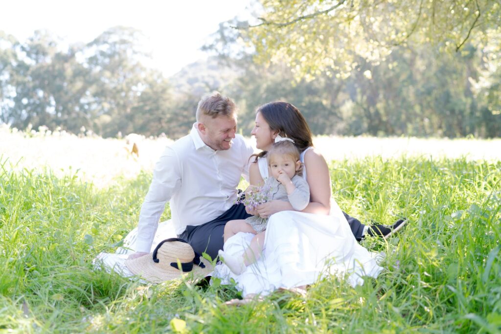 Happy man, happy wife, and their daughter out in the open for a picnic.