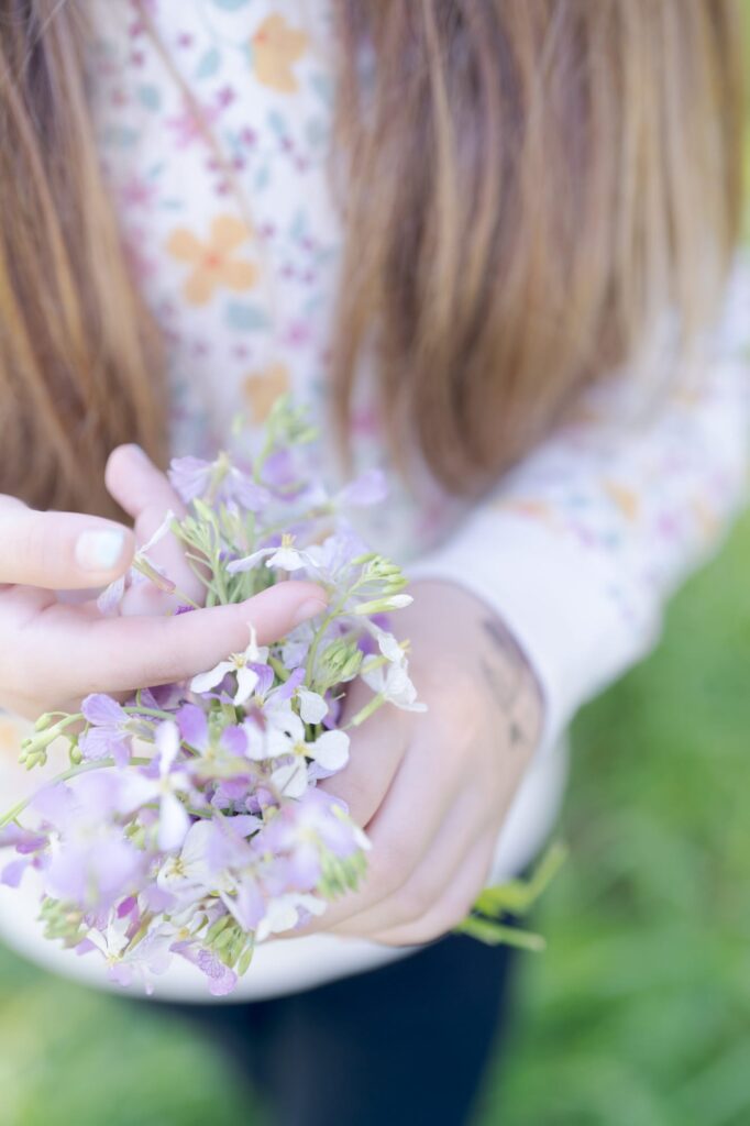 Girl with blond-red hair holds a bouquet of wildflowers.