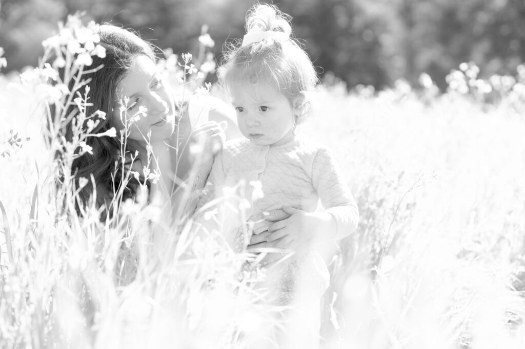 Woman with her daughter amidst tall grasses and wildflowers.