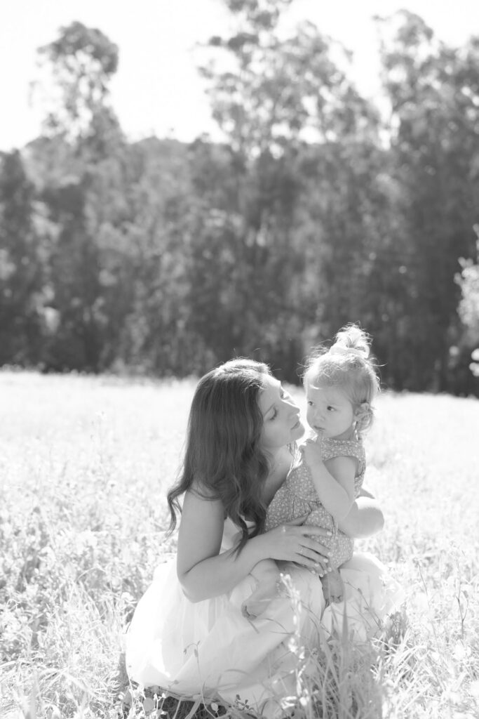 Lady leans into her baby daughter for a peck in the cheek.