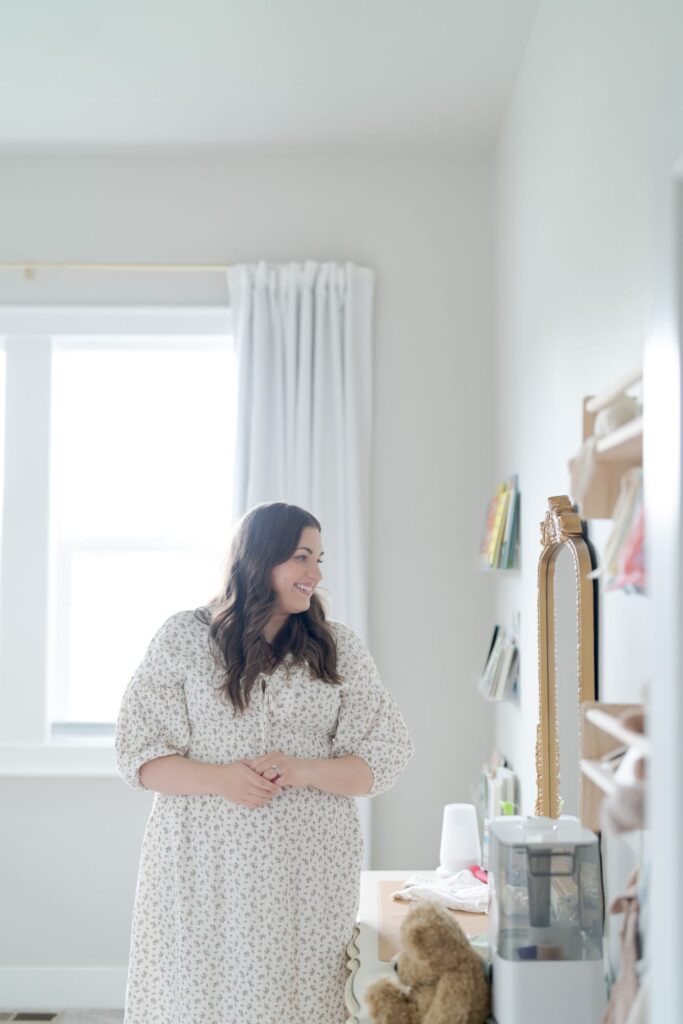 Mom in a loose gown inspects her baby's room.