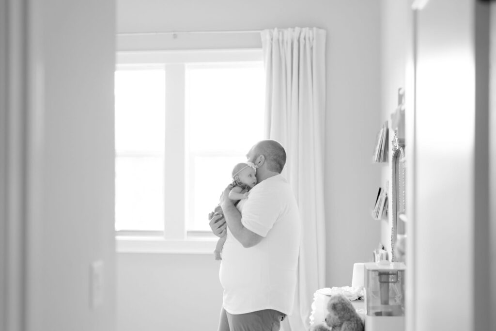 Father holds her newborn baby in his arms.