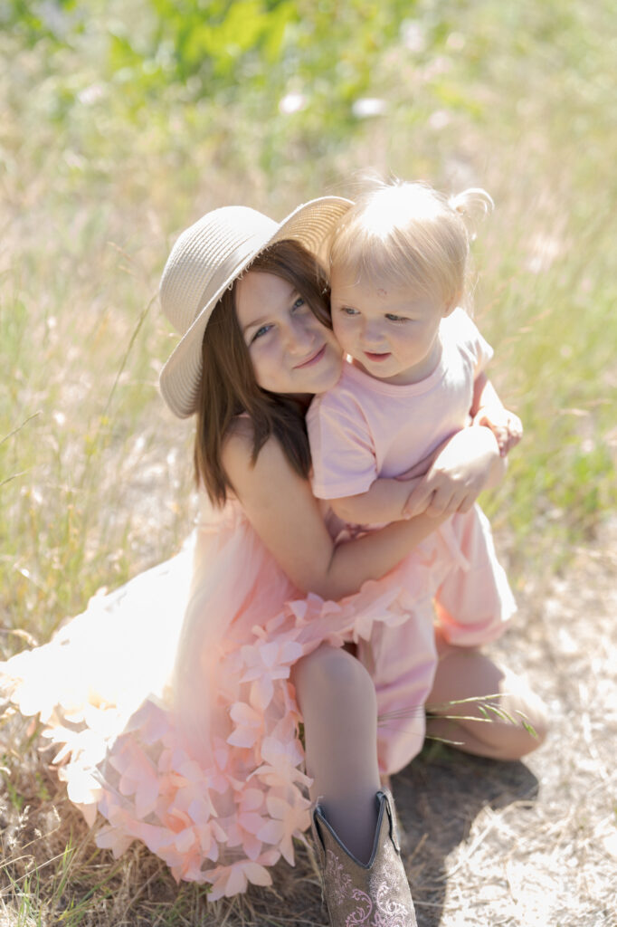 Cute little girl with a sun hat holds her baby sibling.