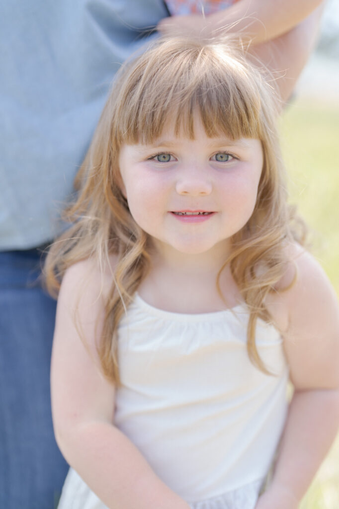 Cute little baby girl in a white dress looks into Robin Jolin's camera.