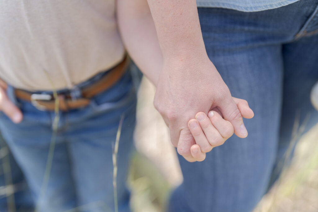 Father and son in blue jeans hold hands.