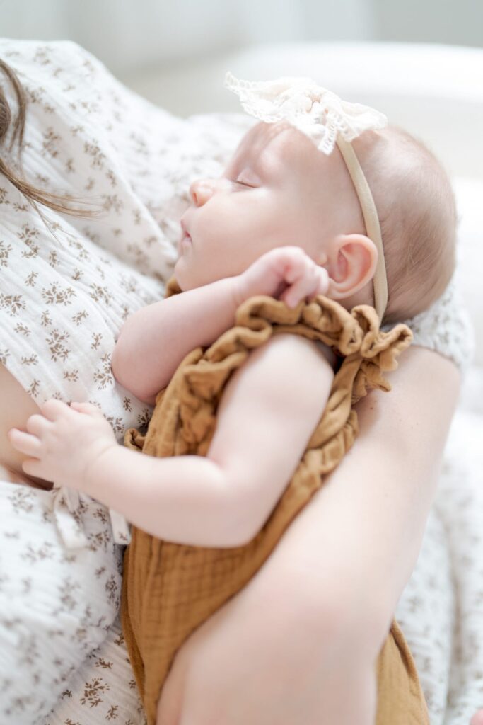 Professional newborn photographer Robin Jolin captures a sleeping baby in their mother's arms.