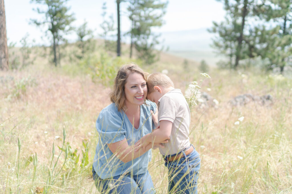 Mom holds her shy son in tall grasses of La Grande.