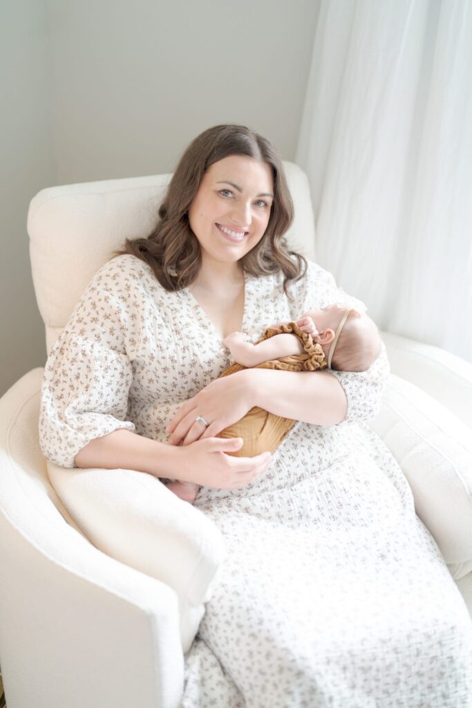 Mom holds her newborn and looks at the camera.