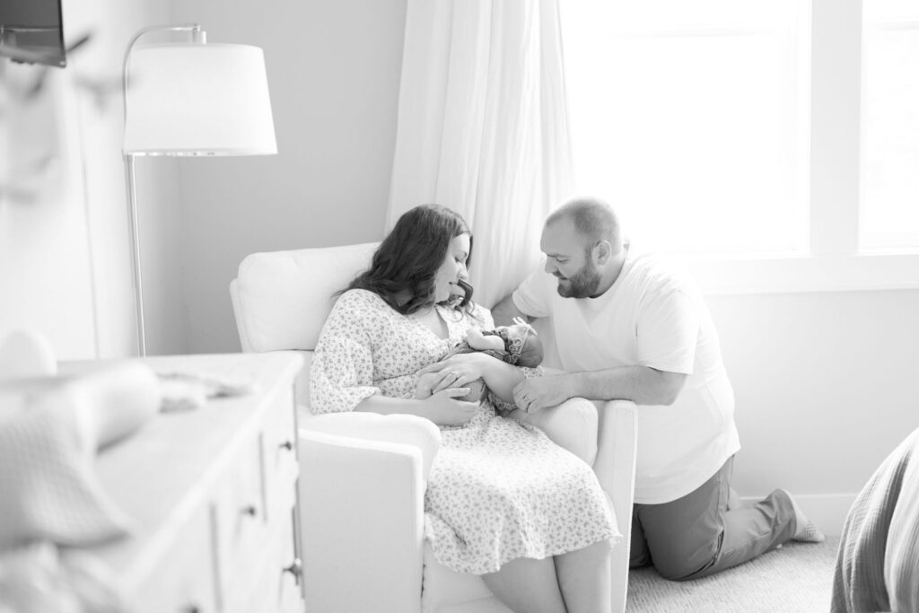 Lady holds her newborn baby in her arms while the father kneels down to comfort her.