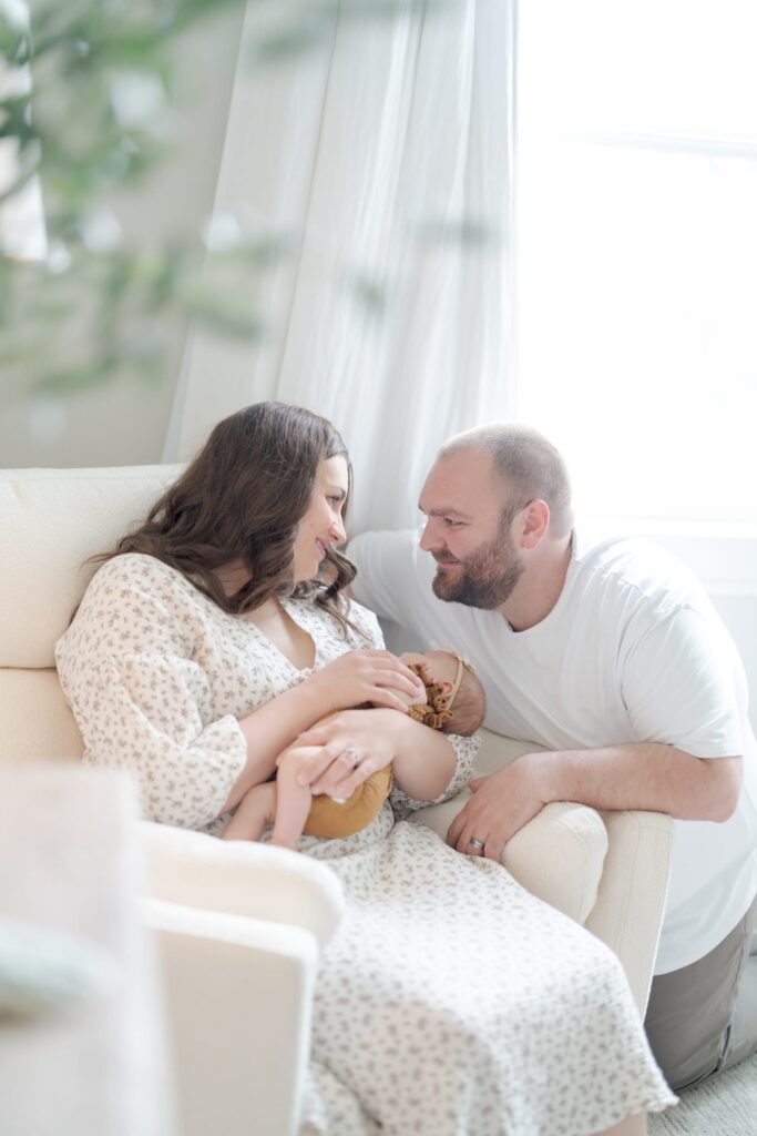 Mom and dad of a newly born look intently at each others' eyes.