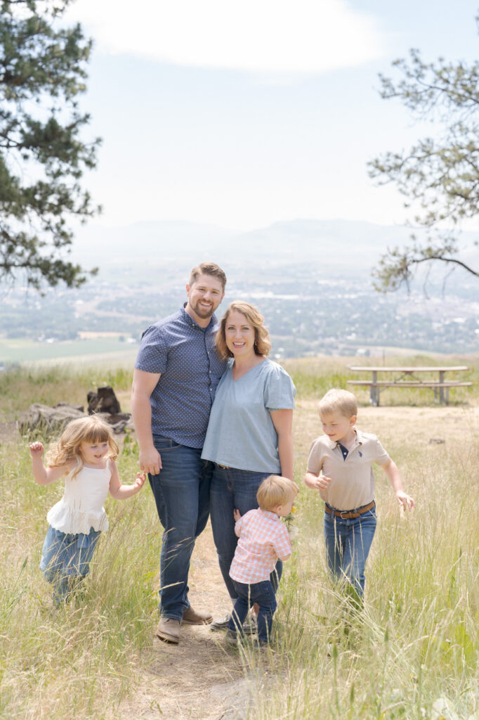 Family portrait photography where the parents stand in the center and 3 children run around them.