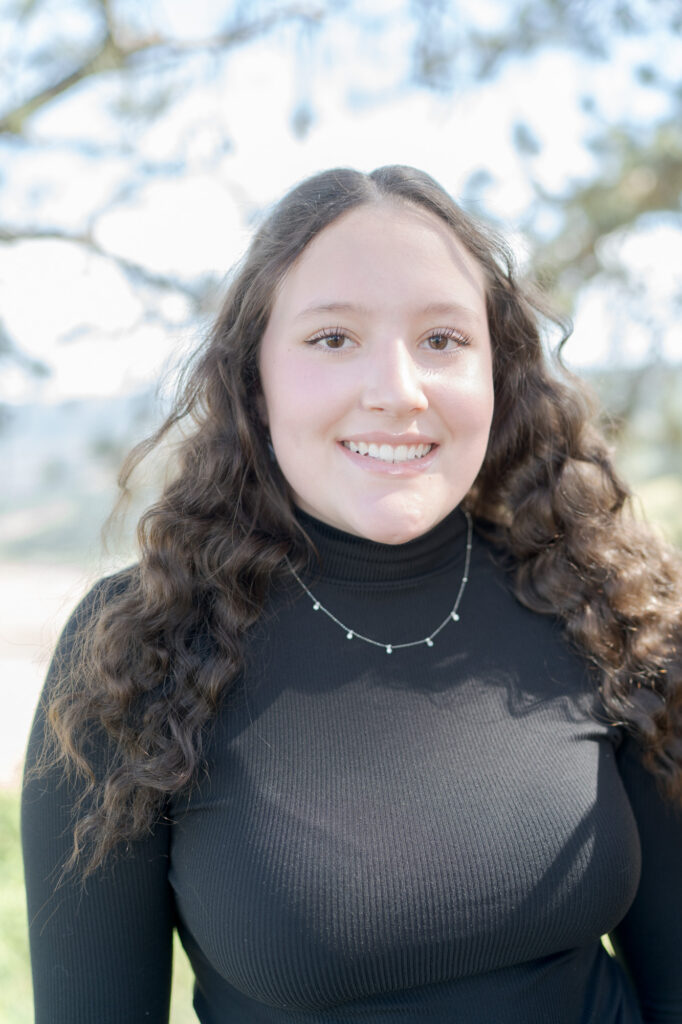 Teenage girl in a black sweatshirt smiles at the camera.