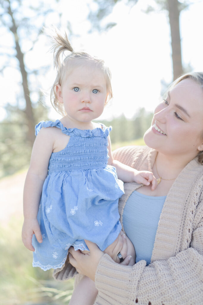 Mom looks passionately at her baby daughter with blue eyes and a blue dress.