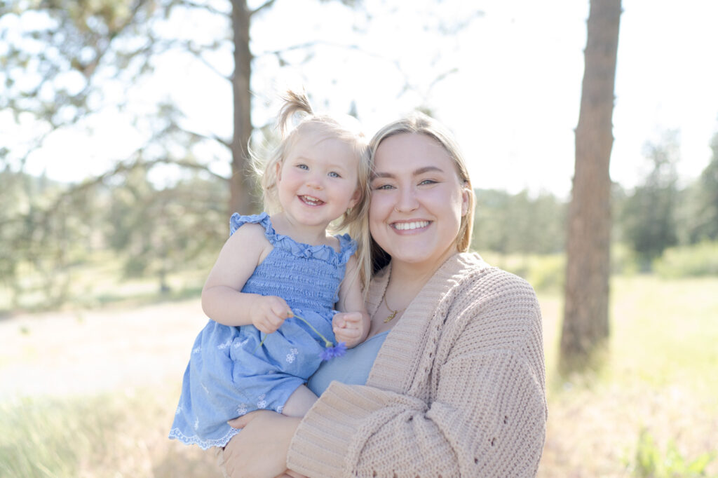 Adorable mom and daughter smile at the camera.