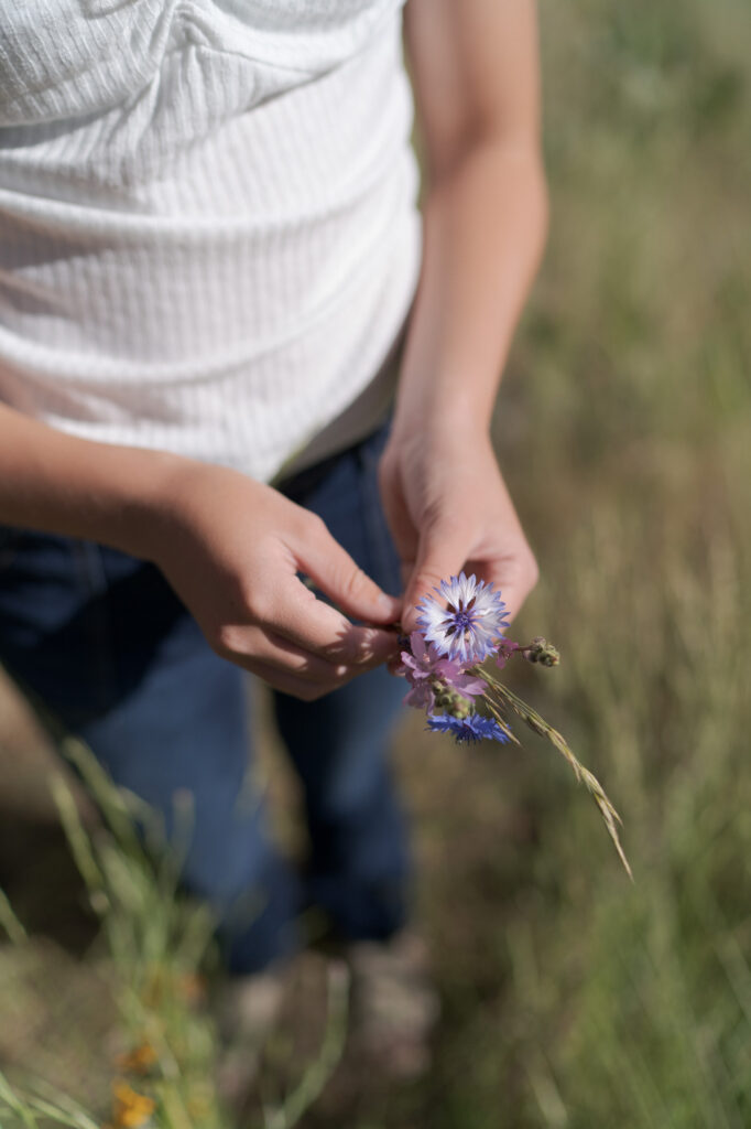 Girl in blue jeans and white tshirt shows her wildflower.