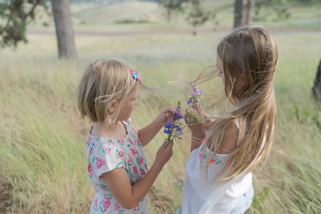 Two little girls compare their wild flowers.