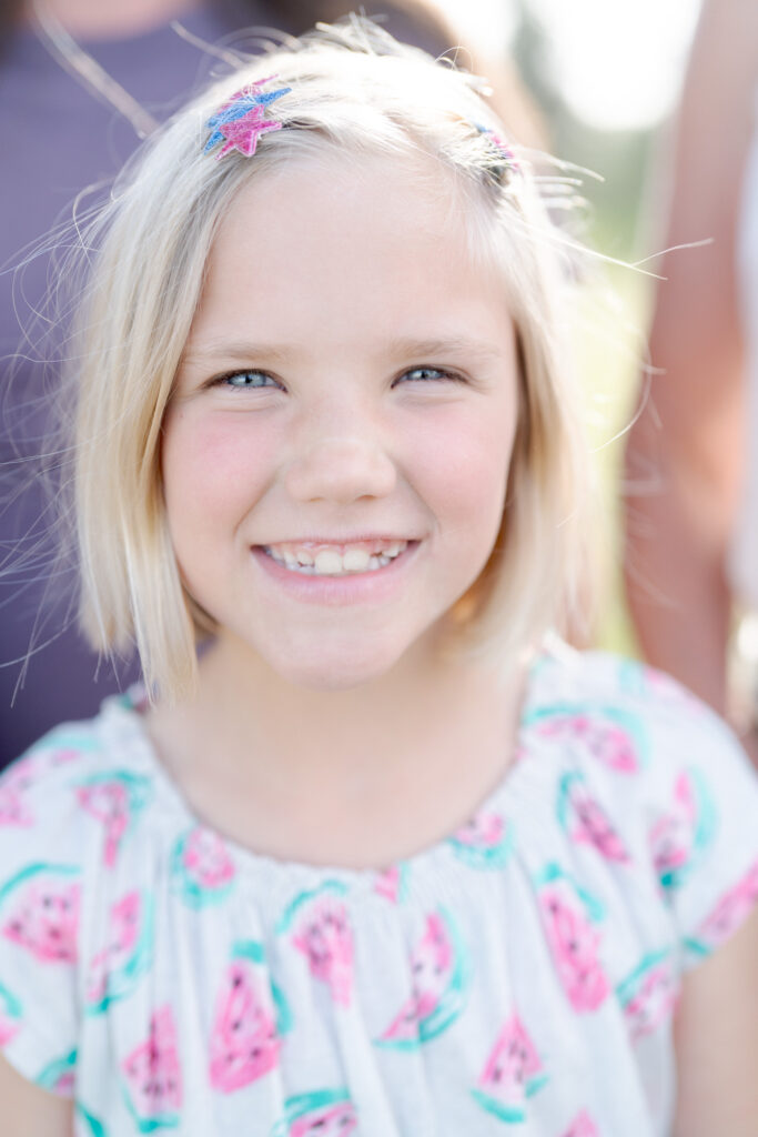 Cute girl wearing a star clip smiles at the camera.