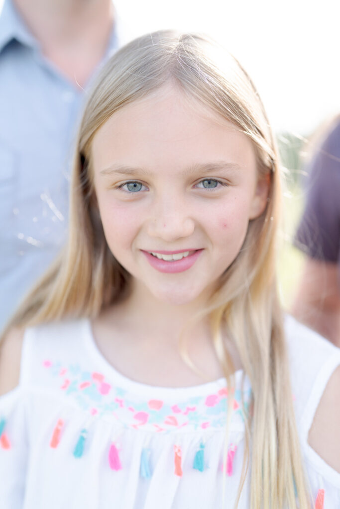 Cute girl with white and pink dress looks at the camera.