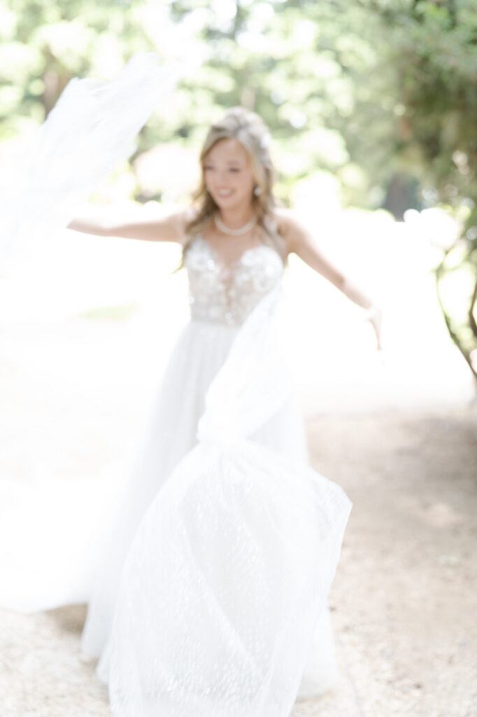 Happy bride in wedding gown spreads her arms.