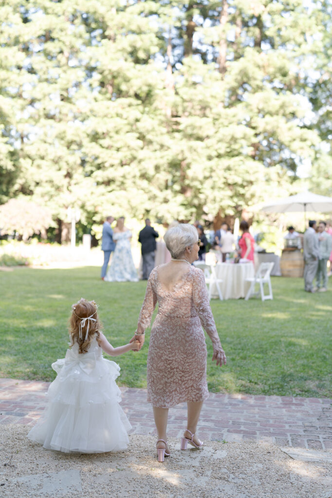 Grandma holds her little granddaughter's hand at the wedding cocktail hour.