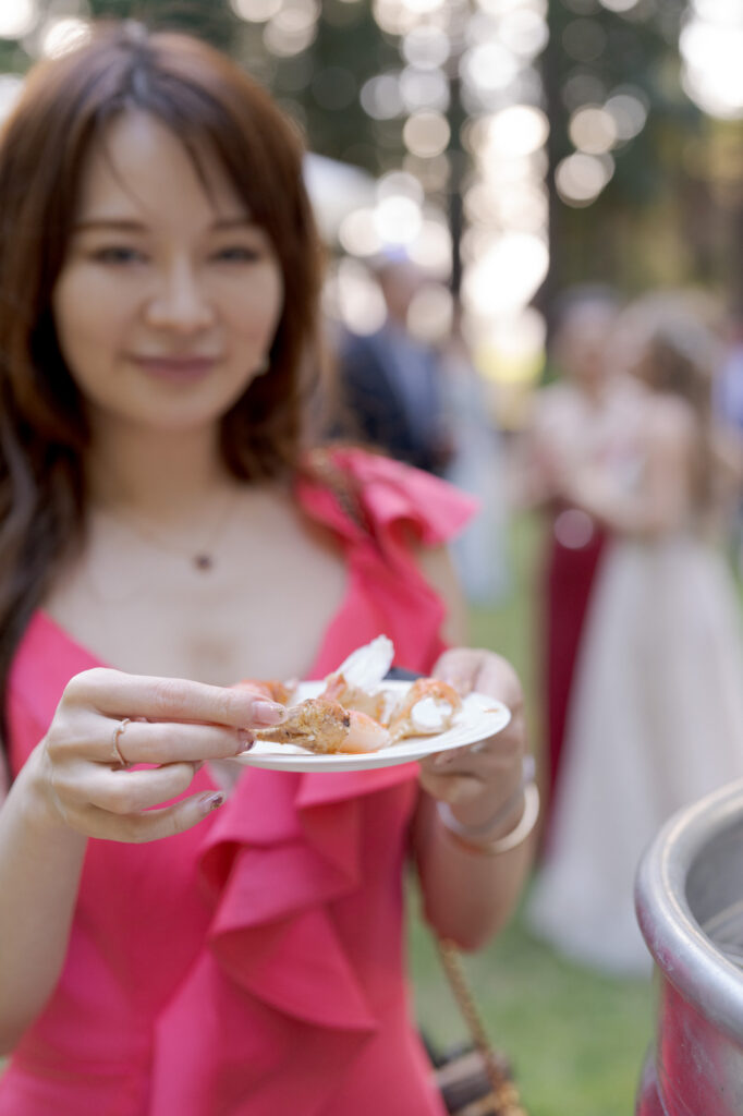 Pretty wedding guest in a red dress shows her plate of cuisines.