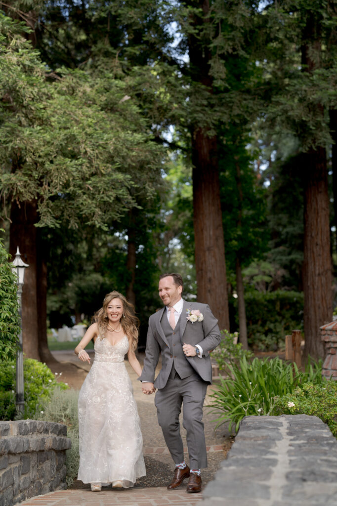 Happy bride and groom walk into a stone bridge.