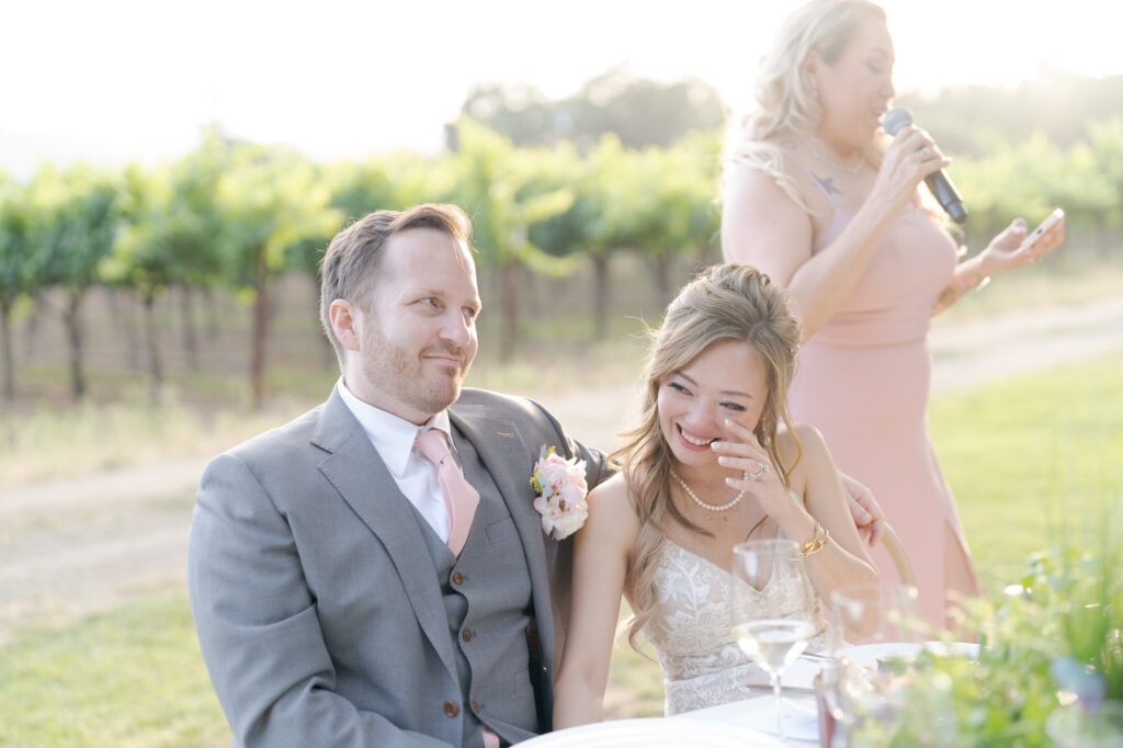 Briedsmaid reads her toast with the bride and groom seated at their table.