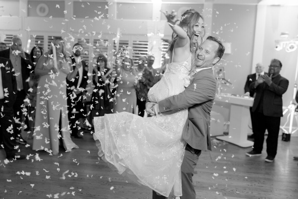 Groom lifts her bride up at a wedding reception party dance.